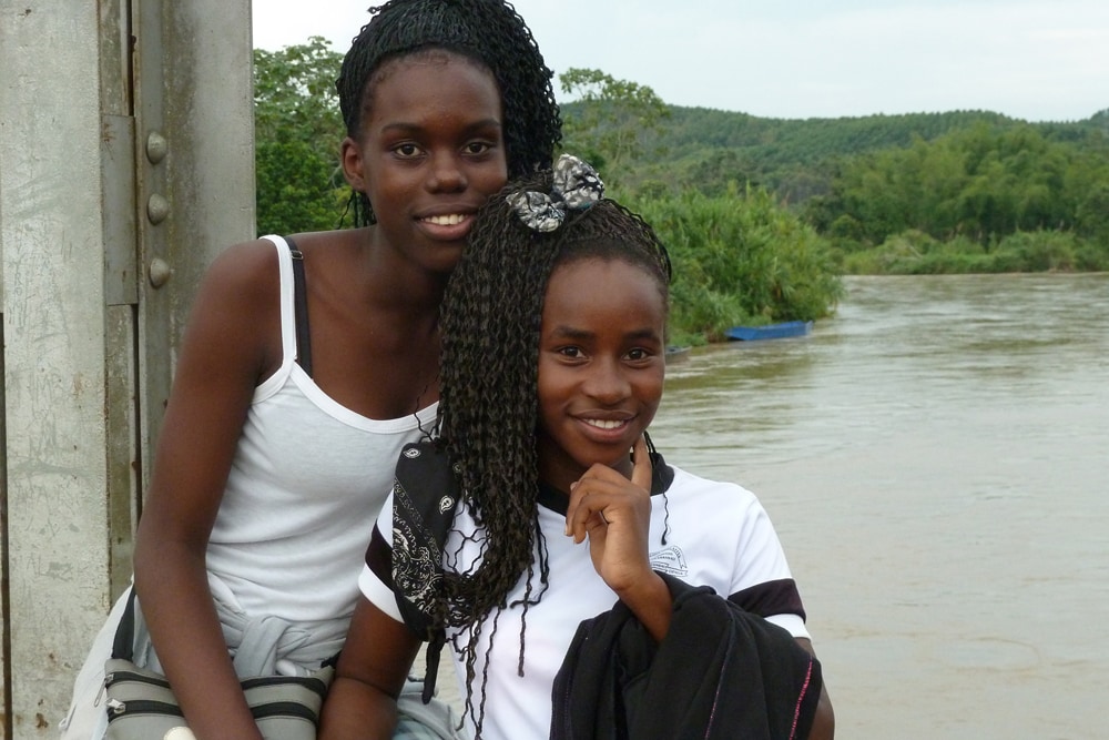 Zwei junge schwarze Frauen aus Kolumbien sitzen nebeneinander.