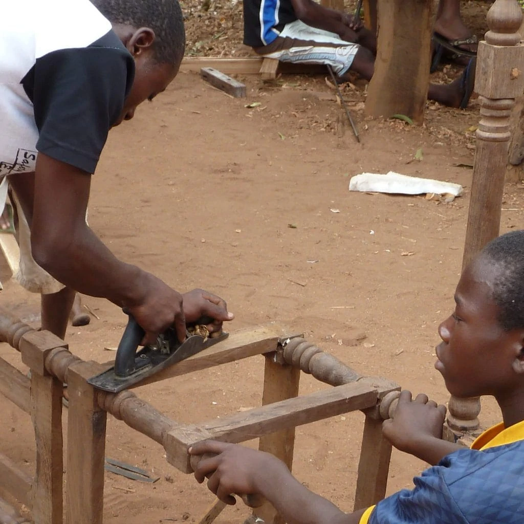 Two youths are grinding a wooden chair in the open air.