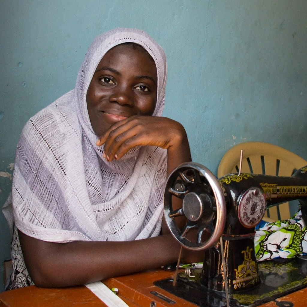 Young black woman at an old, pedal-operated sewing machine.