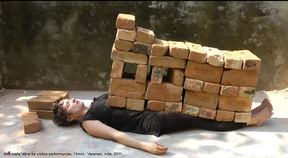 A woman is covered with several dozen bricks.