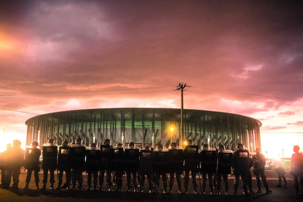 Brazilian security forces stand in front of a football stadium.