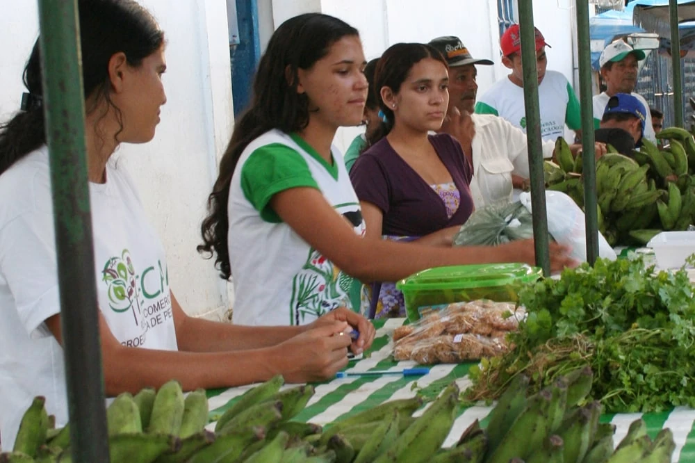 Junge Frauen verkaufen am Marktstand ihre eignen Bananen.