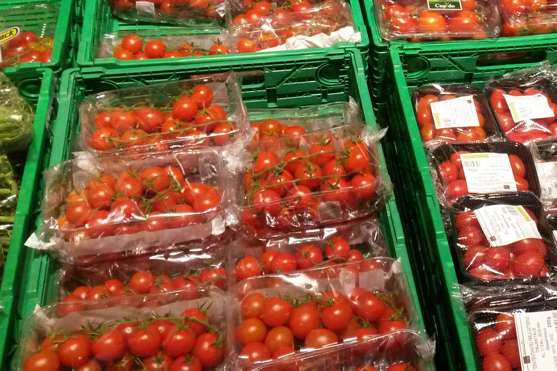 Cherry tomatoes with plastic wrapping in harasses in a supermarket.