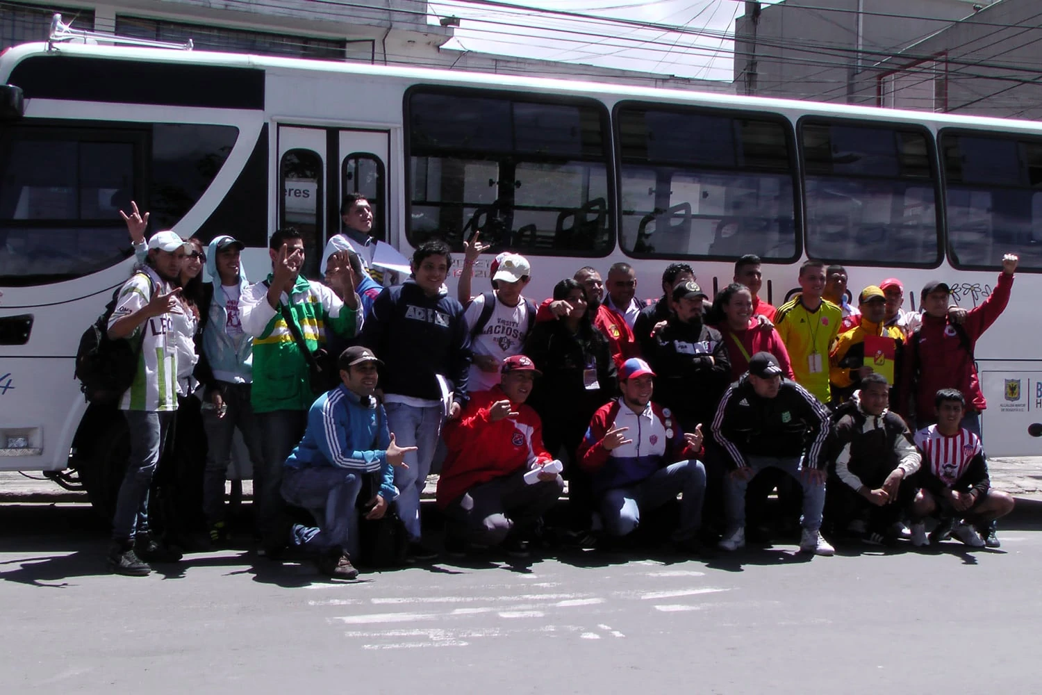 25 Jugendliche von 18 Fanklubs und der FJMBN stehen für ein Gruppenfoto zusammen vor einem weissen Autobus.