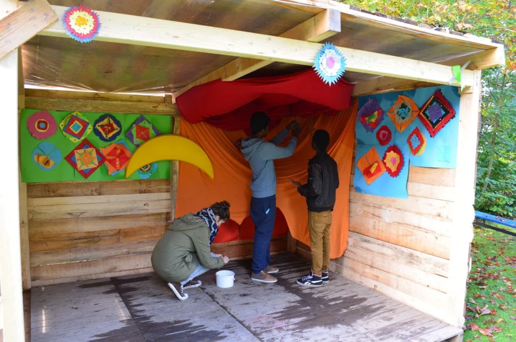 Young unaccompanied asylum seekers build up a stand with the help of young people from imagine.