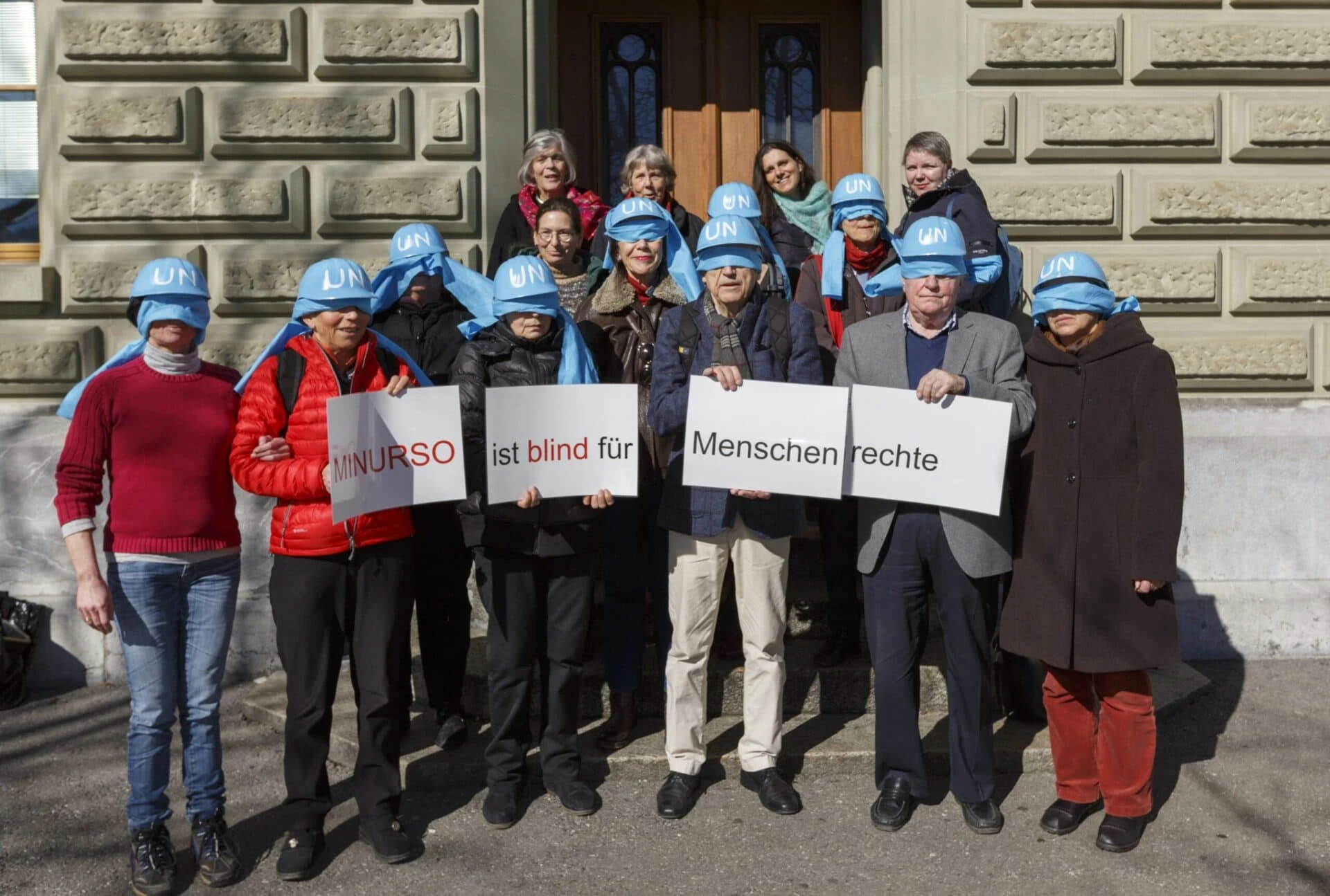 Menschen mit blauen Helmen die den Schriftzug UN tragen stehen zusammen für ein Gruppenbild vor der Bundeskanzlei.