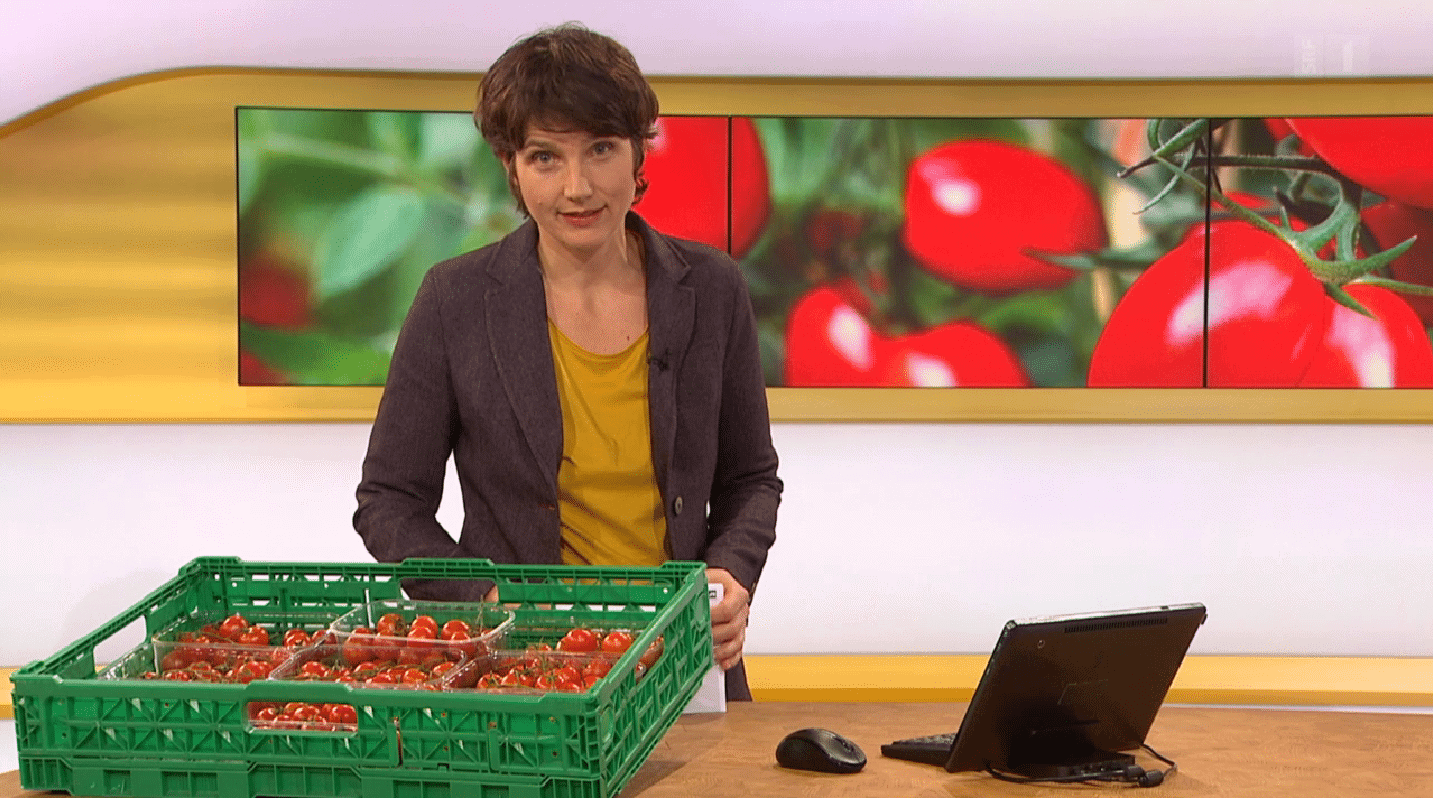 Screenshot aus der Sendung Kassensturz. Die Moderatorin hat Tomaten auf dem Tisch.