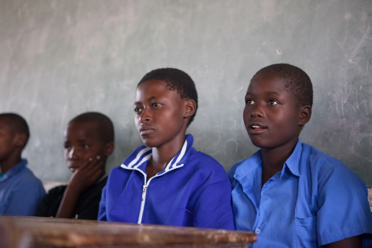 Girls in blue school uniforms look past the camera in concentration.