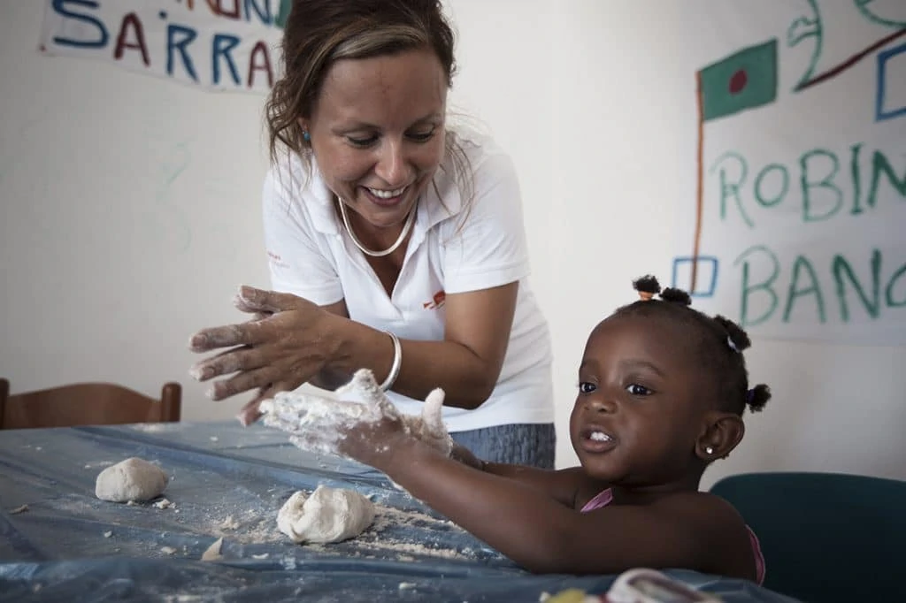 A FARO project worker kneads a dough with a black girl.