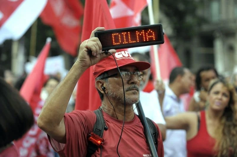 A man holds up an electronic board named Dilma.