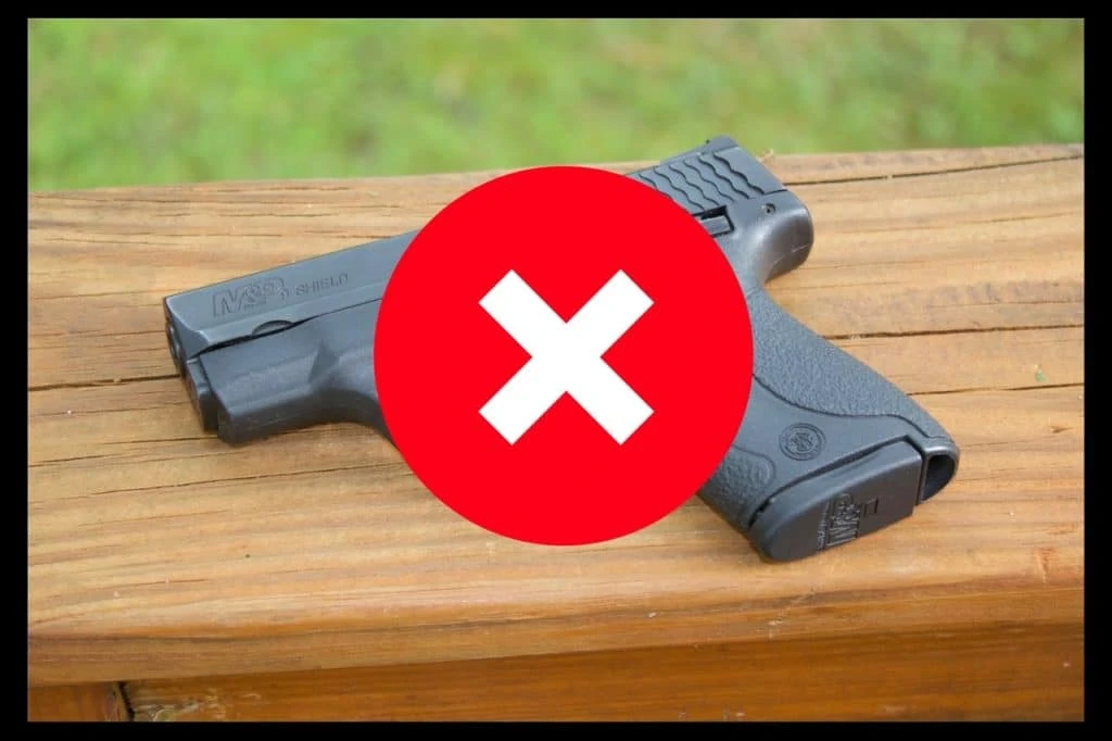 Eine Handfeuerwaffe auf eine Holzgeländer. Darüber ein grosses X mit roter Farbe.
