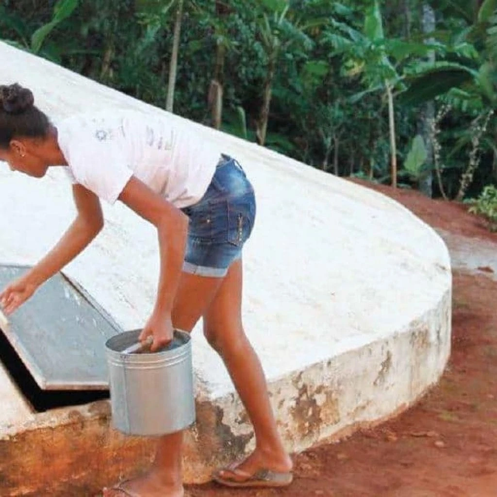 Eine junge Frau holt Wasser aus einer weissen