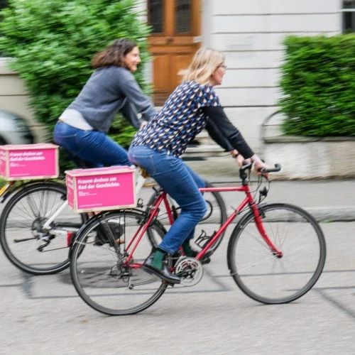 Zwei Fahrradfahrerinnen mit Werbung für den Frauenstreik.