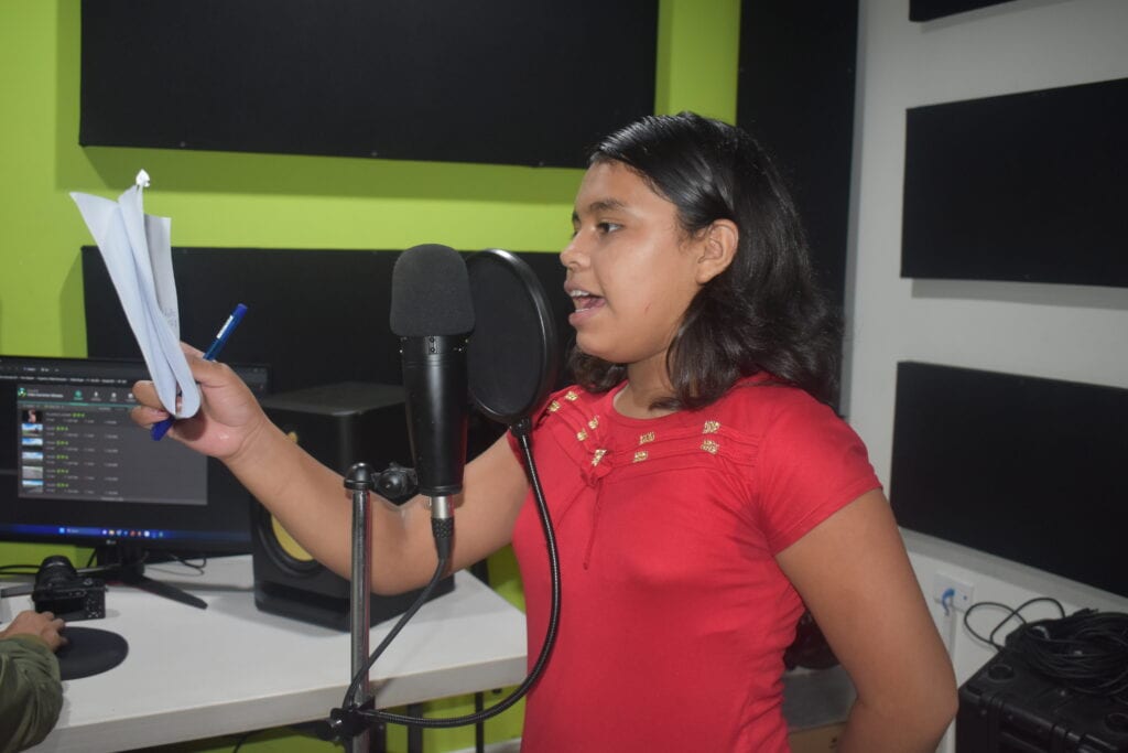 Ein-Mädchen-spricht-in-einem-Radioraum-einen-Text-ins-Mikrofon