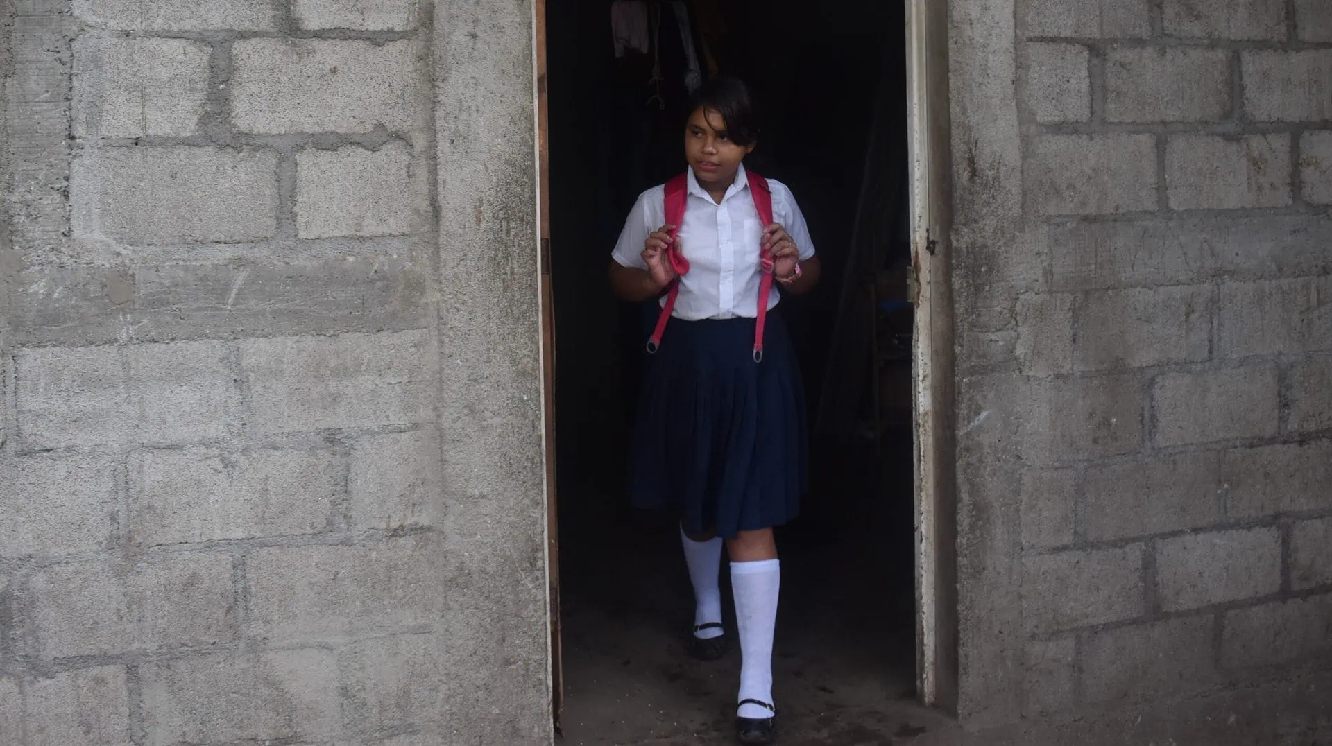 A-girl-in-school-uniform-standing-in-a-doorway.