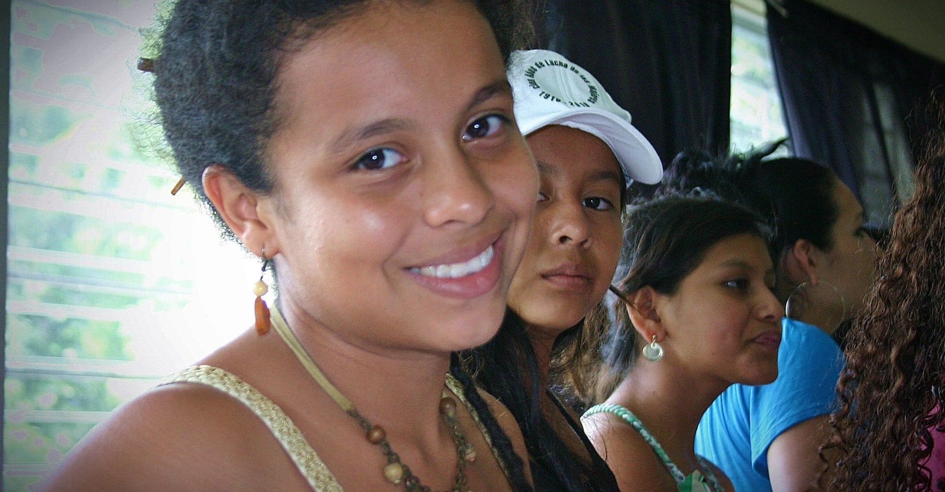 Picture of a young woman with short hair from El Salvador looking into the camera from the side.