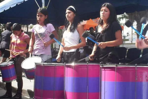 Young women from Las Melidas beat on big drums at a public rally.