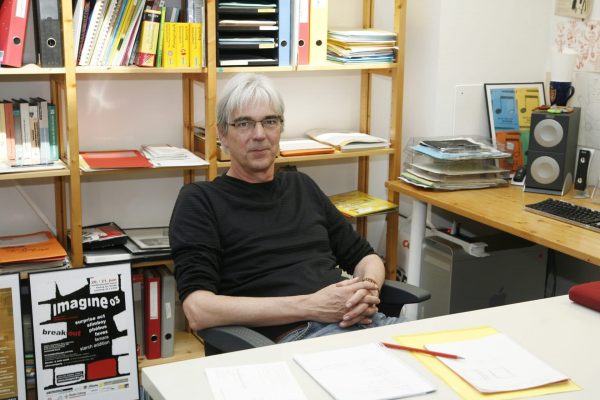 Stefan Studer at his desk in front of a shelf wall.