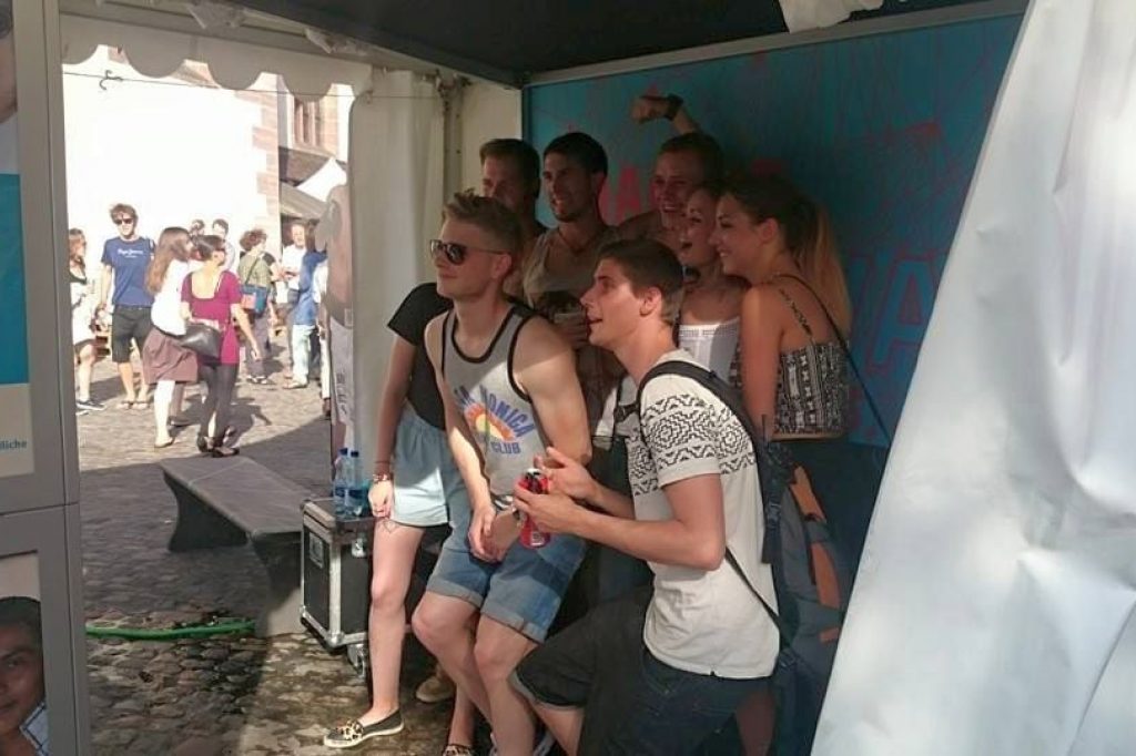 Jugendliche stehen im Zelt vor der Fotobox und lassen sich gemeinsam fotografieren.